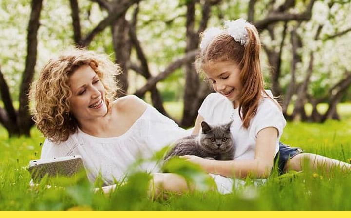 Майка чете книга на дъщеря си, докато държи котка